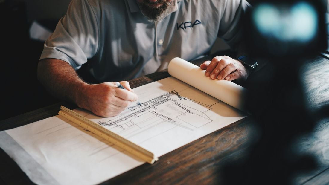 An estimator working over construction drawings at a drafting table