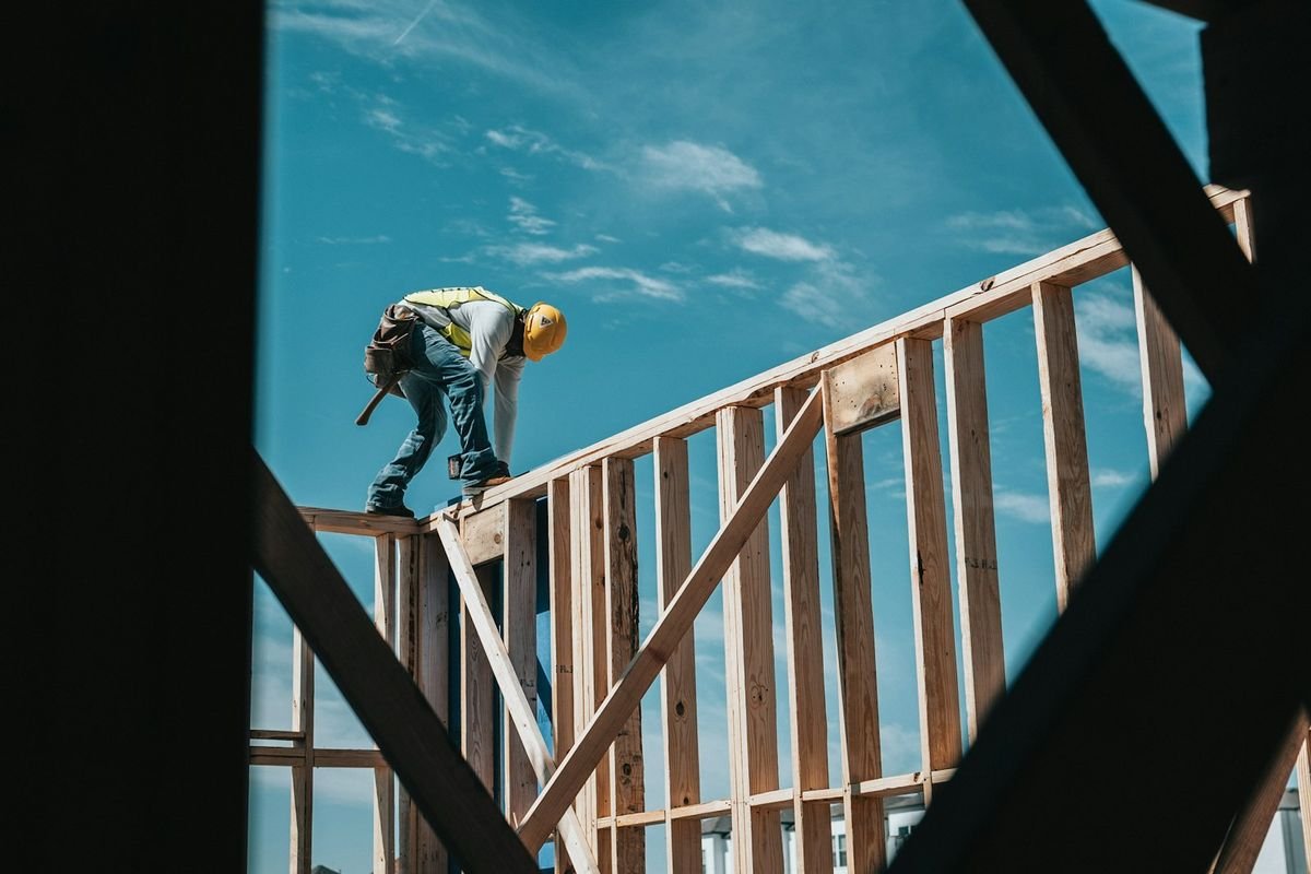 A framer working on a timber structure against an open sky